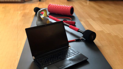 Laptop auf Yogamatte mit Hanteln
