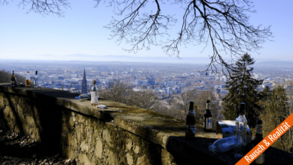 Bier- und Schnapsflaschen vor Panorama der Stadt Freiburg