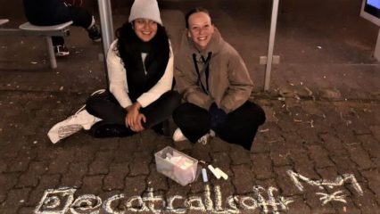 Nele und Sandra knien vor dem Catcallsoffr-Schriftzug